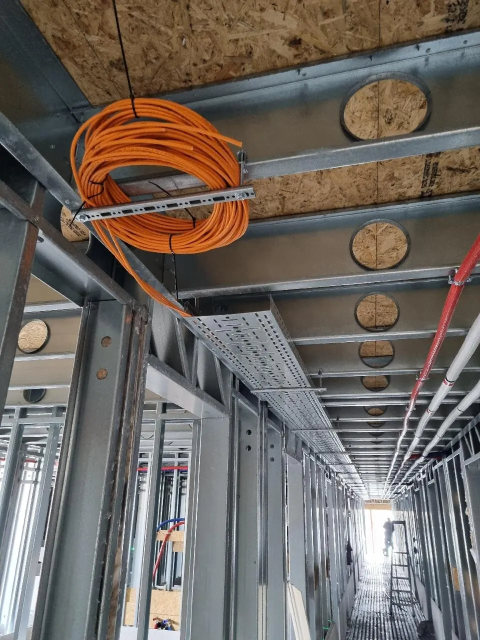 Oranje kabelrol aan het staal van de bouw in Hoofddorp, met een kabelgoot door de gang