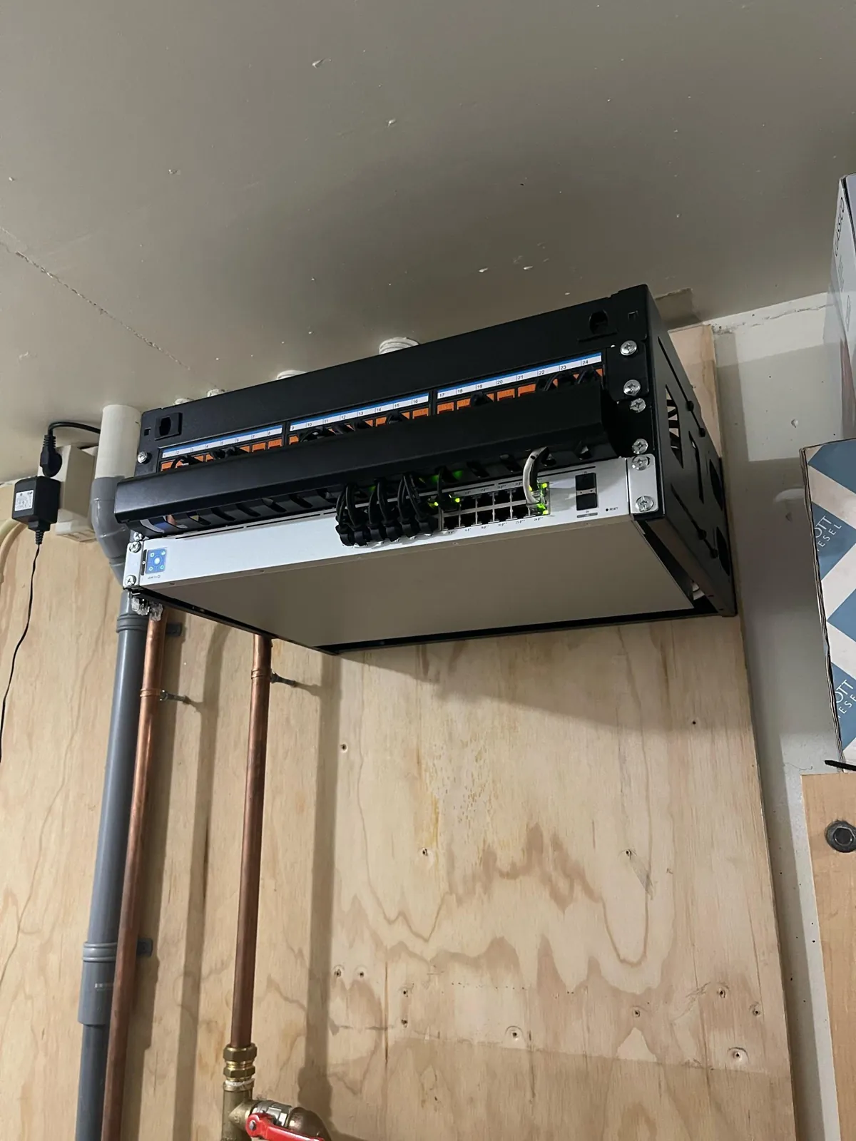Oranje genummerde keystones en korte patchkabels naar de 24-poorts PoE-switch van UniFi in Buren