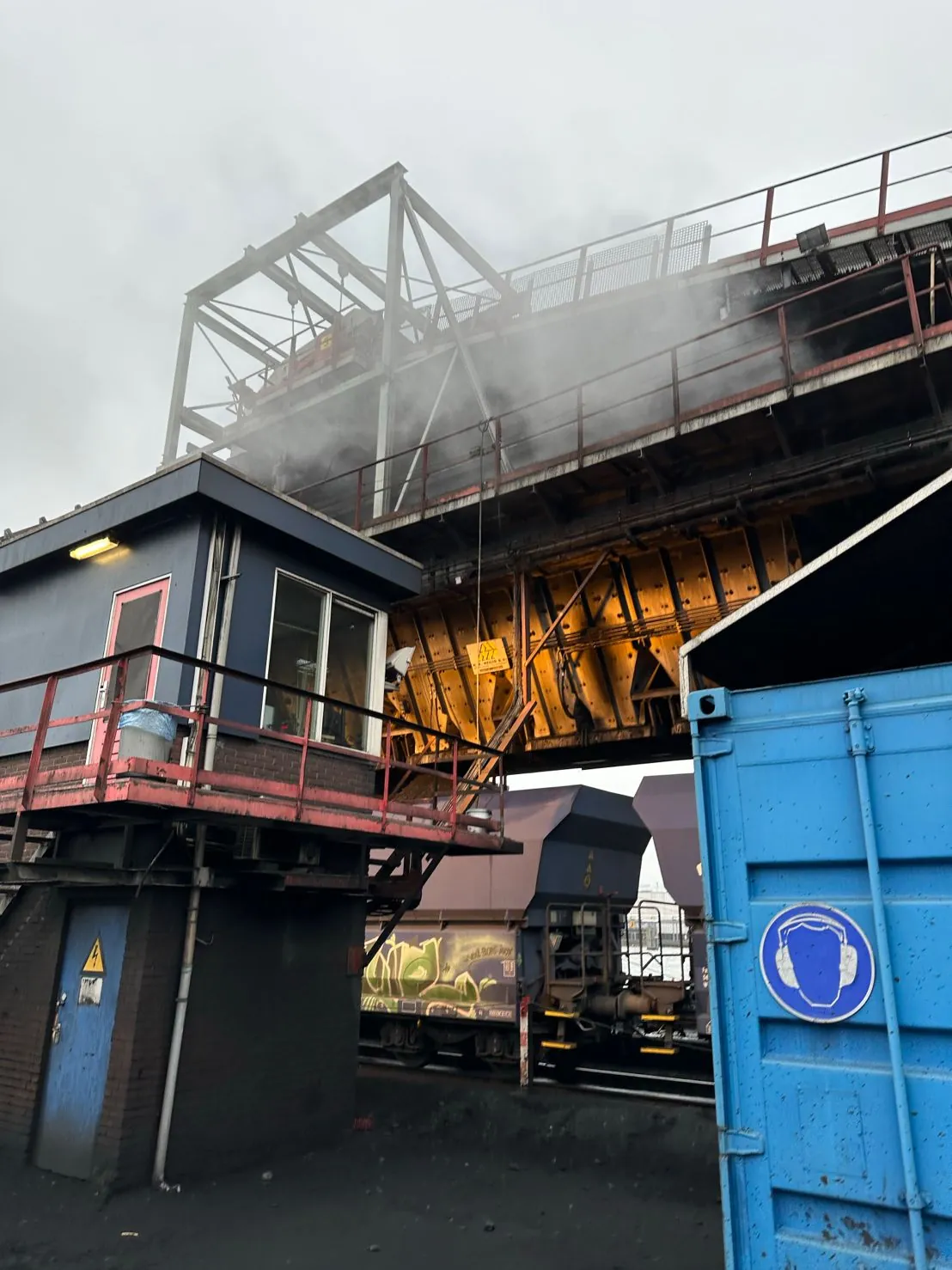 Laadbrug met bedieningscabine boven treinwagons, op een overslagterrein in de Amsterdamse haven