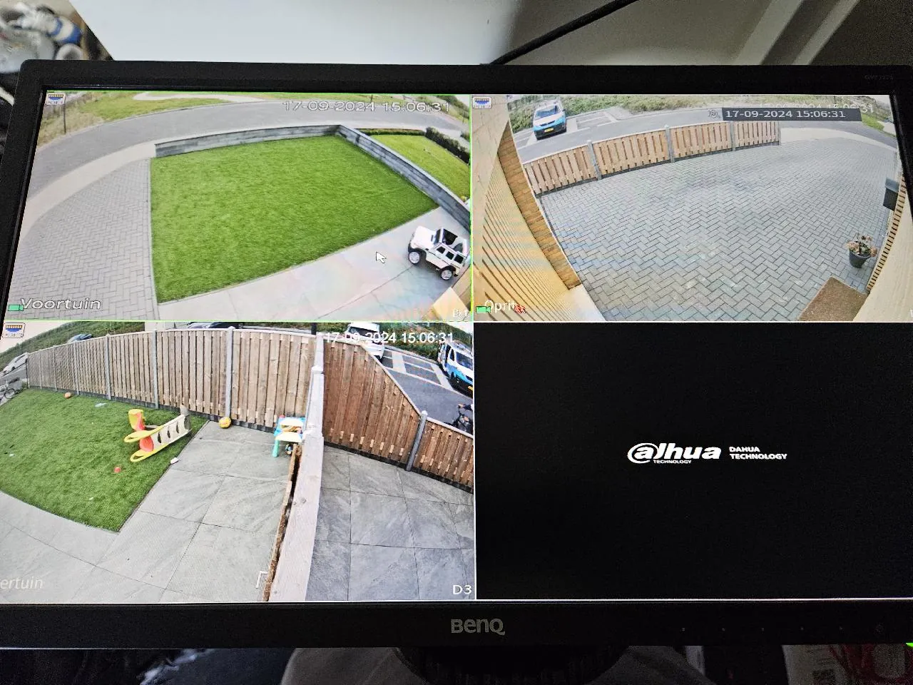 Scherm met camerabeelden van de achtertuin, de oprit en de voortuin