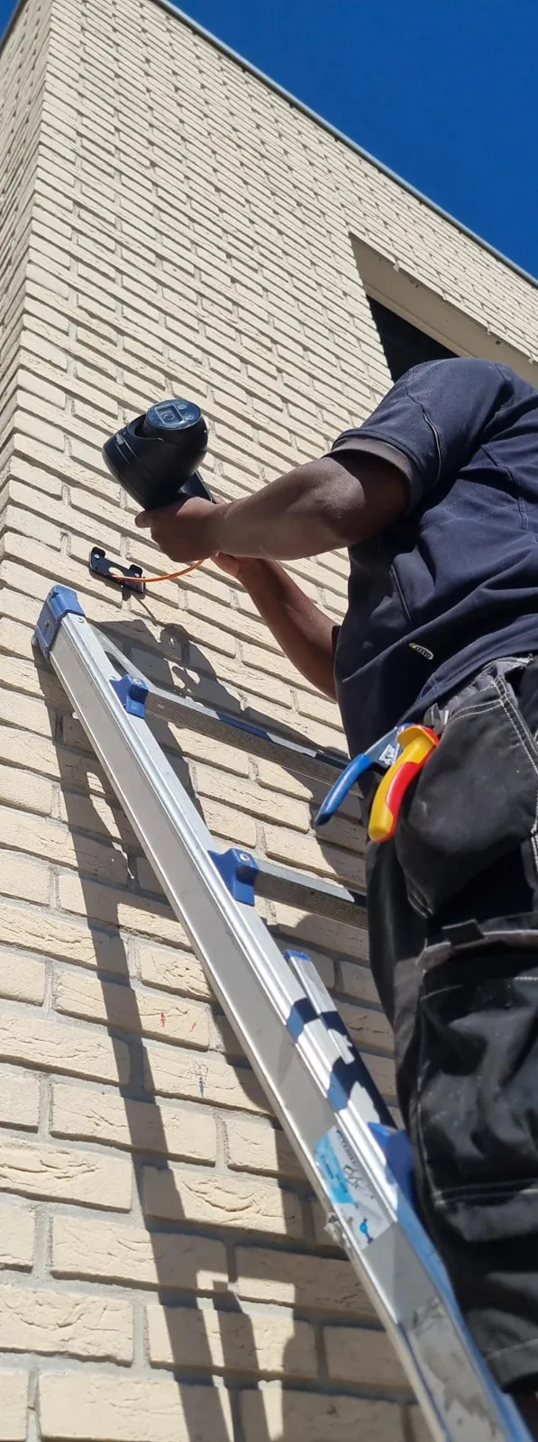 Monteur op een ladder bevestigt een Dahua-camera op het metselwerk van de egelopvang in Papendrecht
