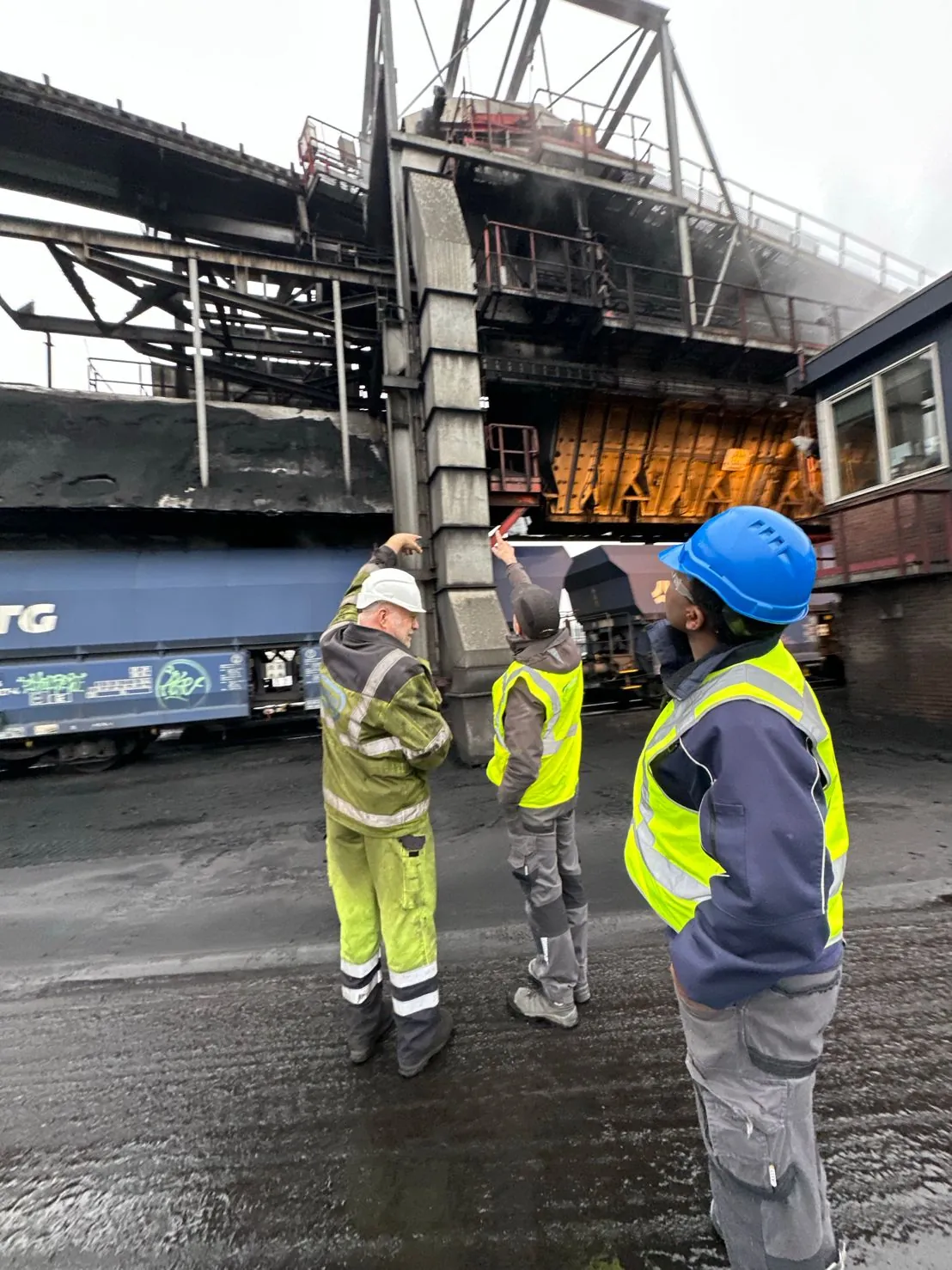 Monteurs in werkkleding bekijken de laadbrug op de bulkterminal in Amsterdam, met volle wagons