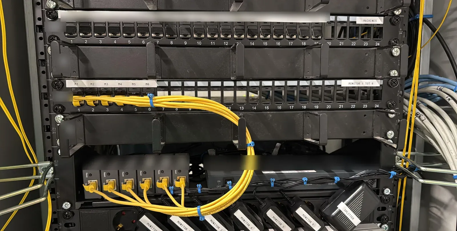 Patchkast in Alkmaar met HDMI-extenders, gele patchkabels, een verdeler en gelabelde voedingen
