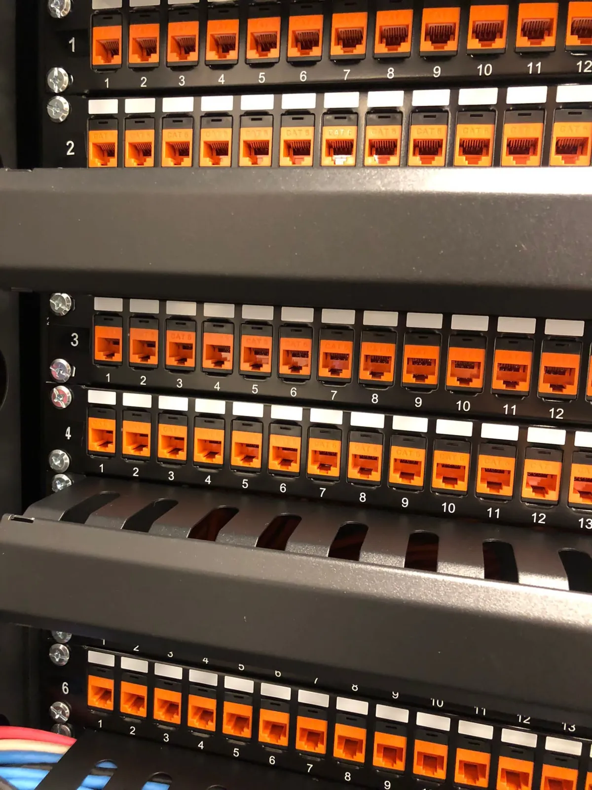 Genummerd patchpaneel met oranje Cat6-aansluitingen in een vernieuwde patchkast van het hotel in Hoorn