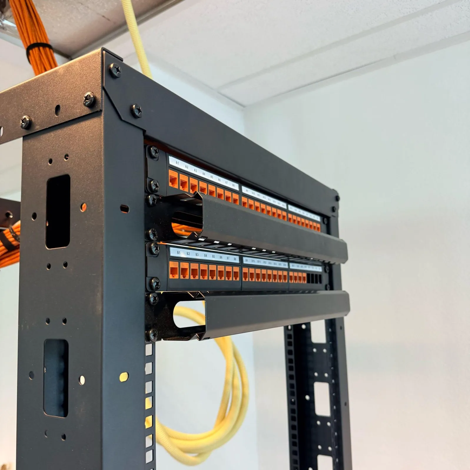 Patchpanelen in een open rack met oranje keystones, genummerd van A1 tot B8