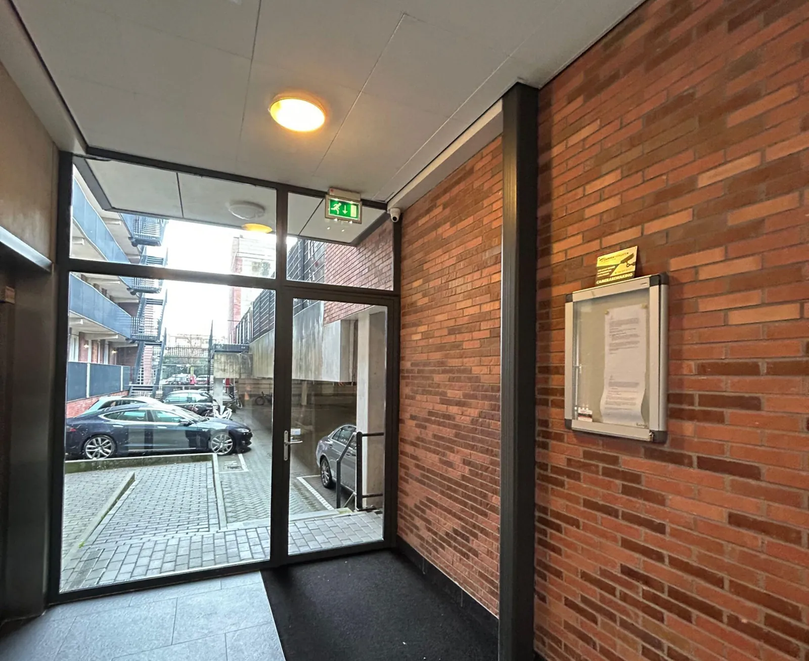 Portiek met glazen pui van een appartementencomplex in Amsterdam, binnenterrein zichtbaar
