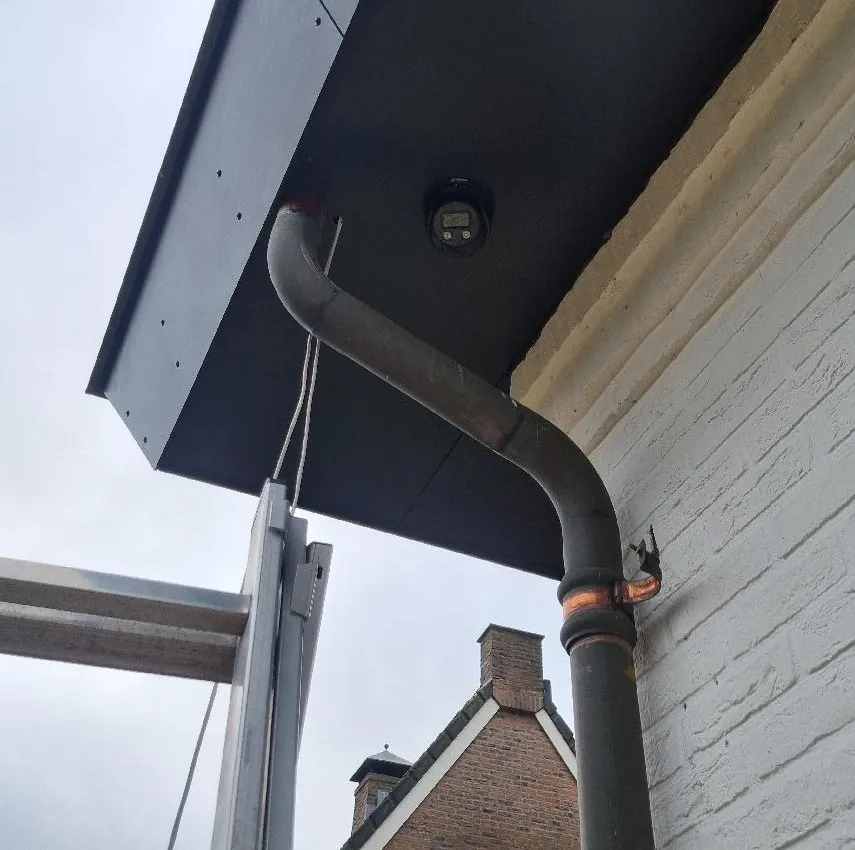 Zwarte turretcamera vlak in het zwarte boeideel van een woning in Nijkerk, naast de regenpijp