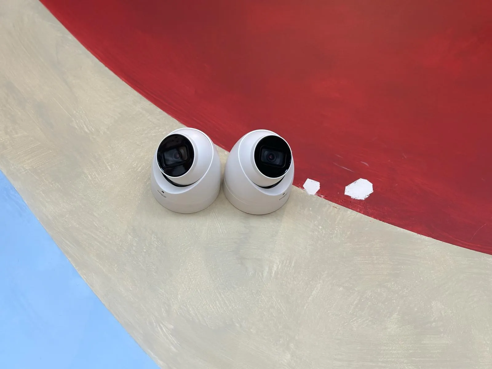 Twee witte turretcamera's op de gebogen rood en crème buitenmuur van het hotel in Amsterdam