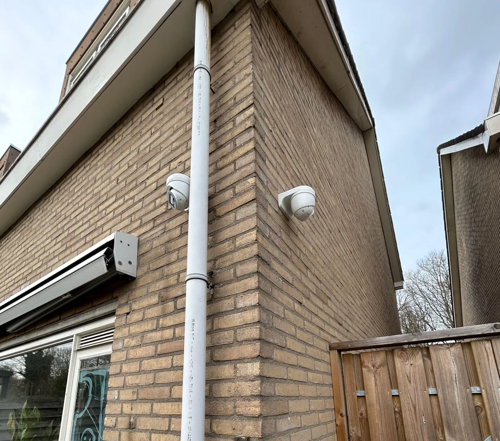 Twee witte camera's op de bakstenen gevelhoek van een woning in Lelystad, elk een andere richting op