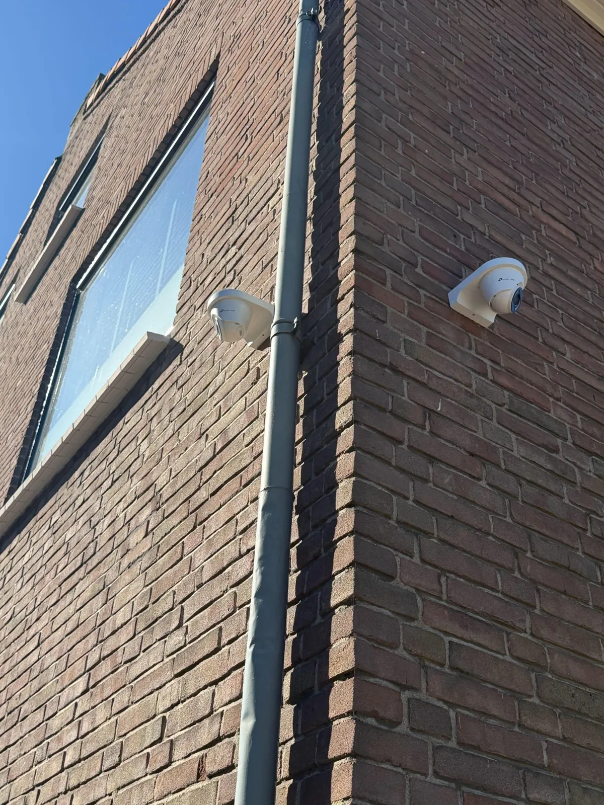 Twee witte VIGI-turrets op de hoek van een bakstenen gevel in Beusichem