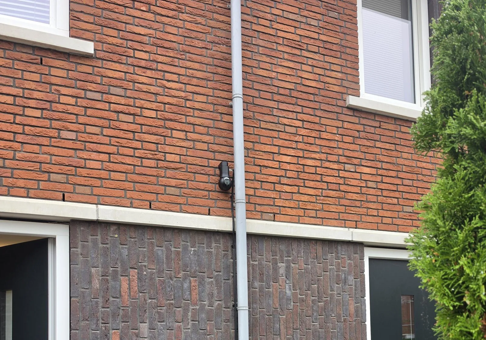 Zwarte UniFi-camera halverwege de achtergevel van een huis in Ridderkerk, bij de regenpijp