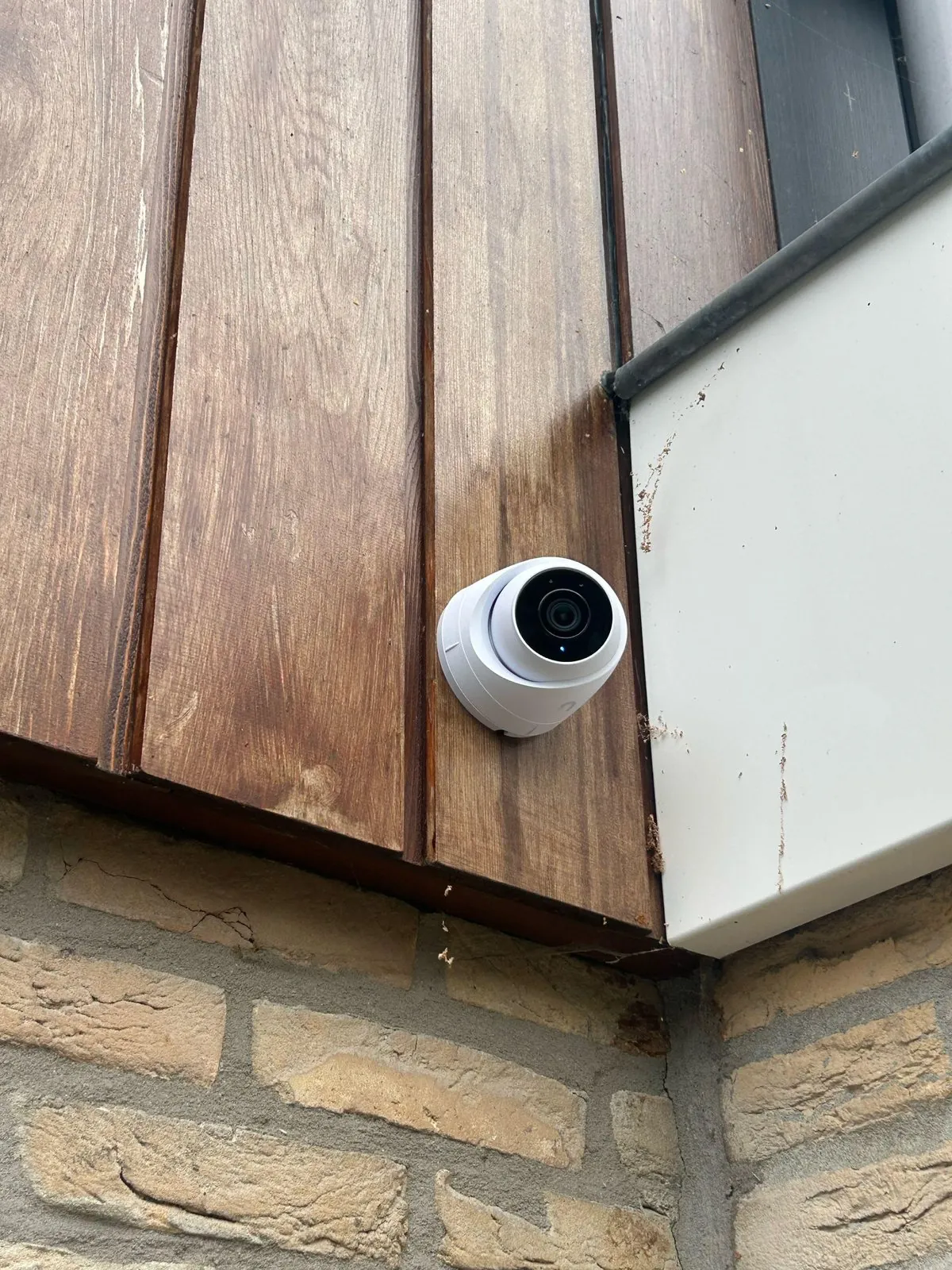 Witte UniFi-camera op de hoek van een gevel in Bunnik, gericht op de achtertuin
