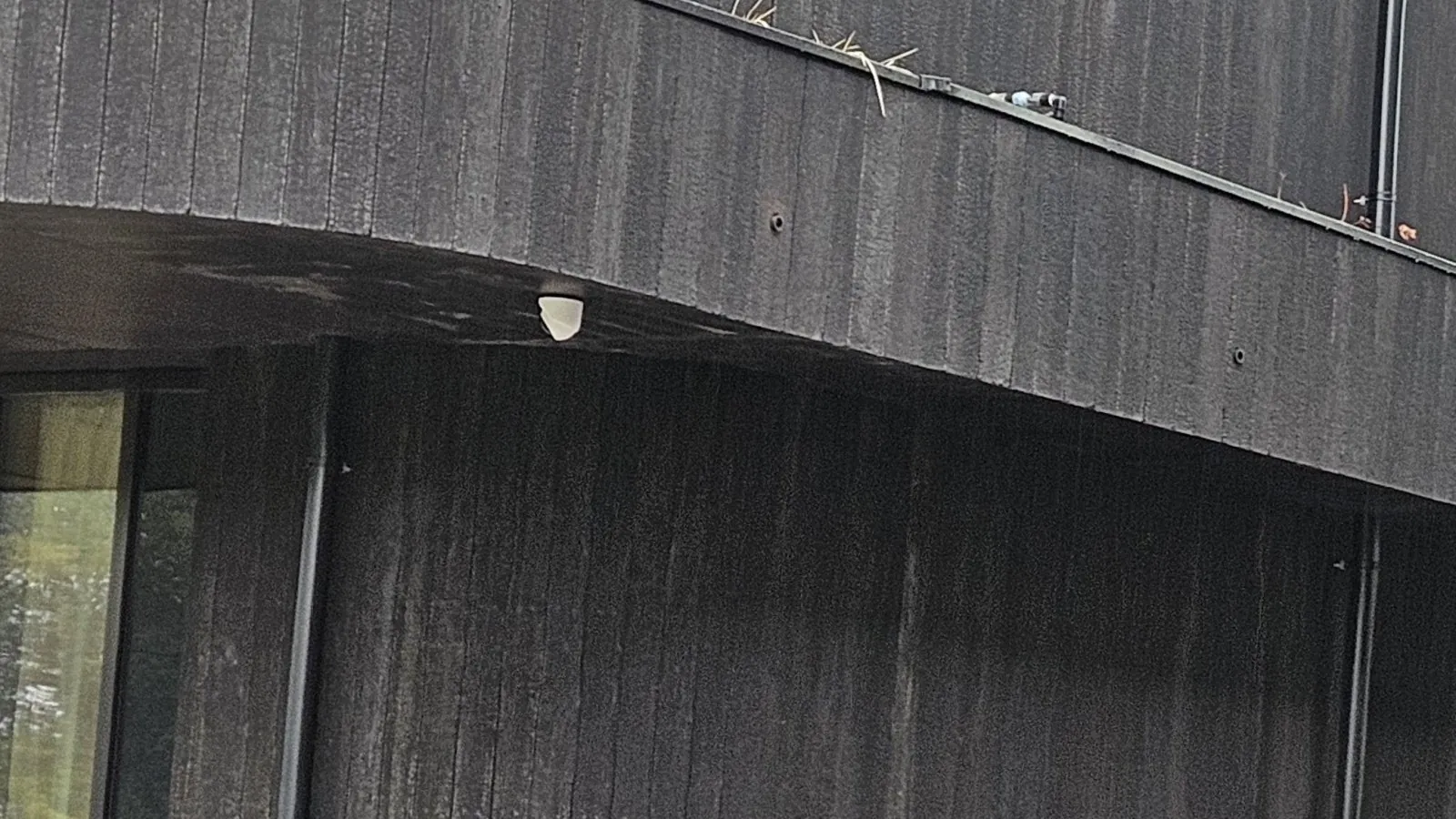 UniFi-camera onder de uitkragende gevel bij de entree van een hotel
