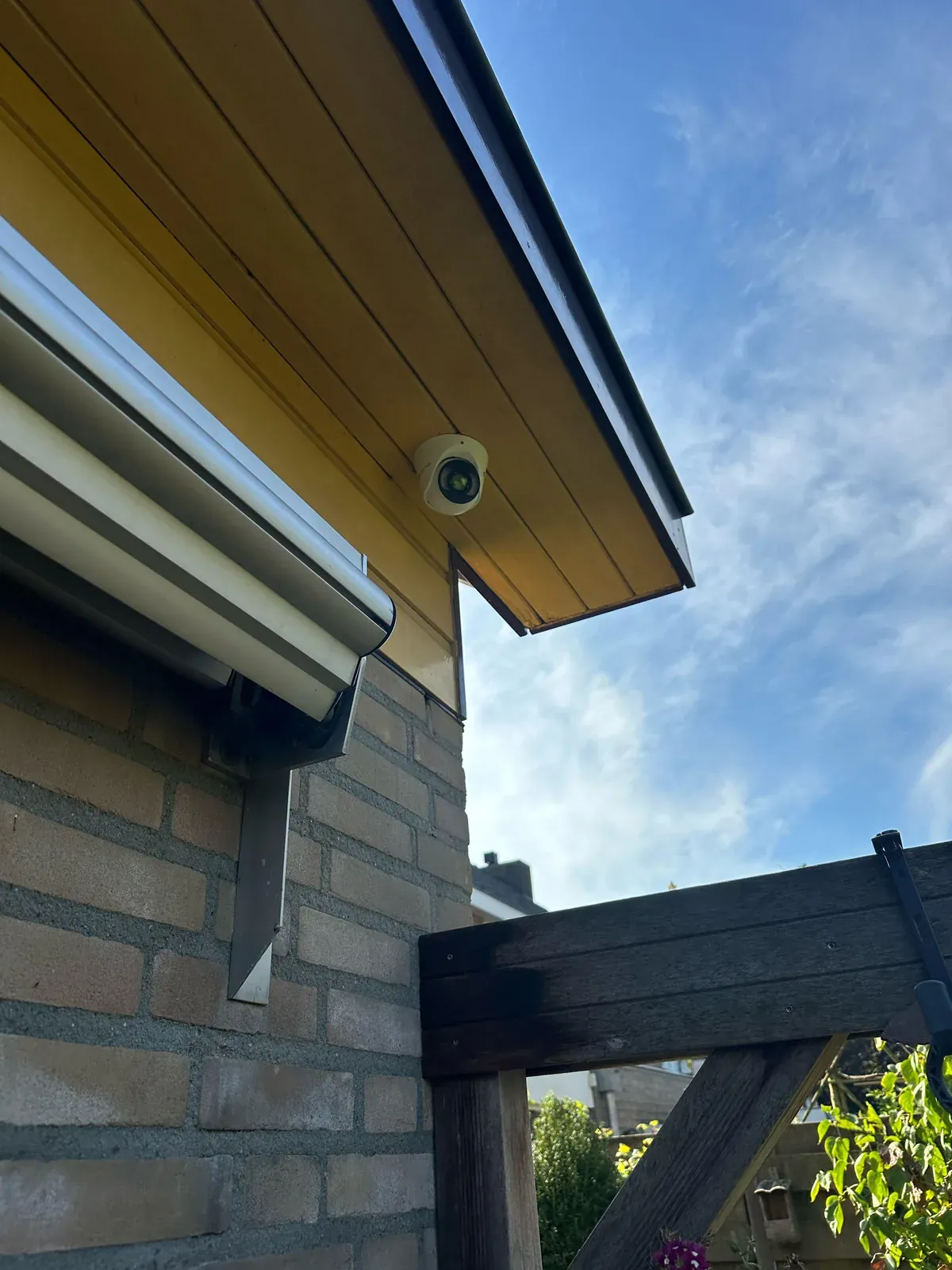 Witte VIGI-camera aan de achterkant van een woning in Sint-Michielsgestel, tussen zonnescherm en tuinpoort