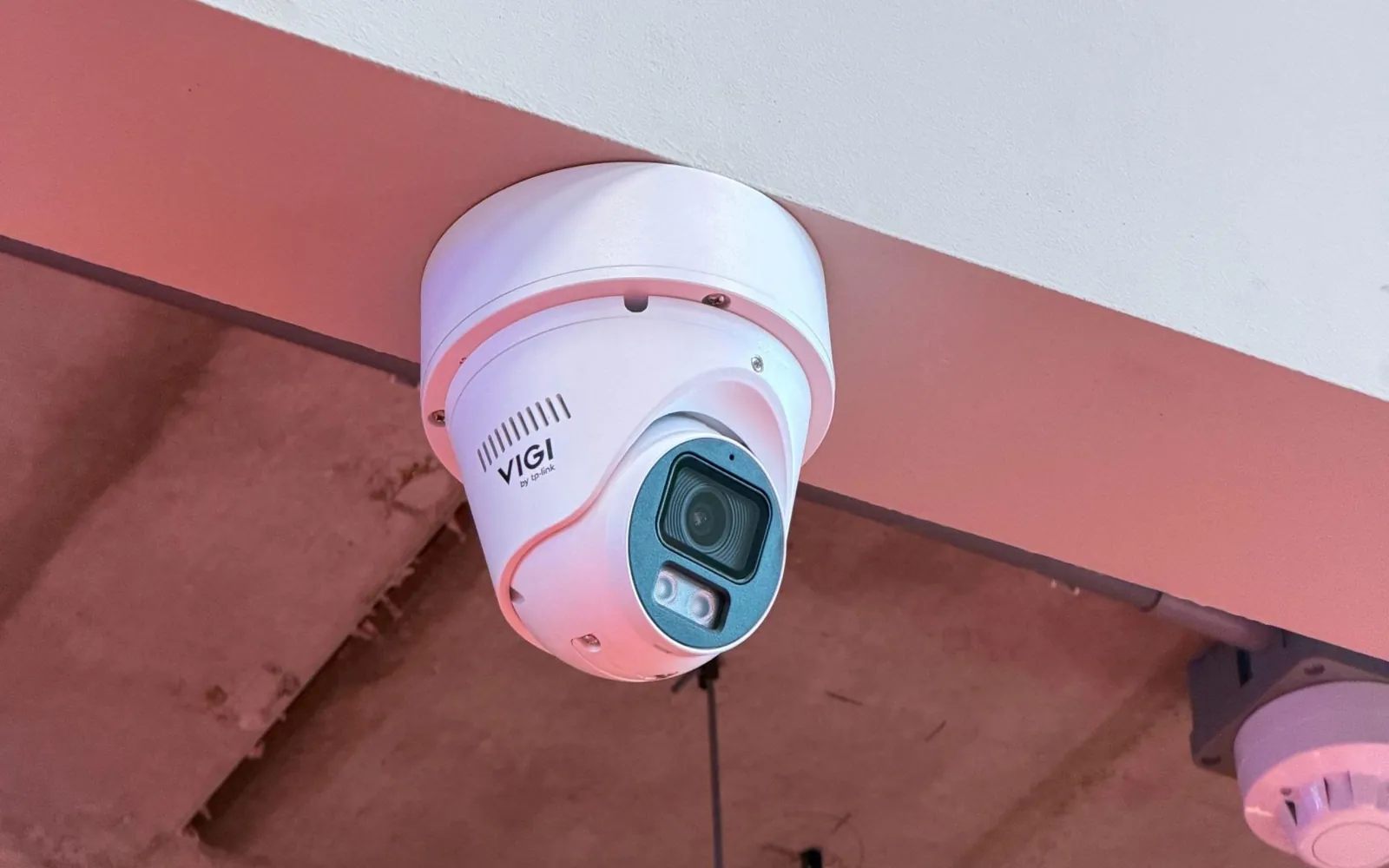Witte VIGI-dome tegen de plafondrand van een salon, naast een rookmelder