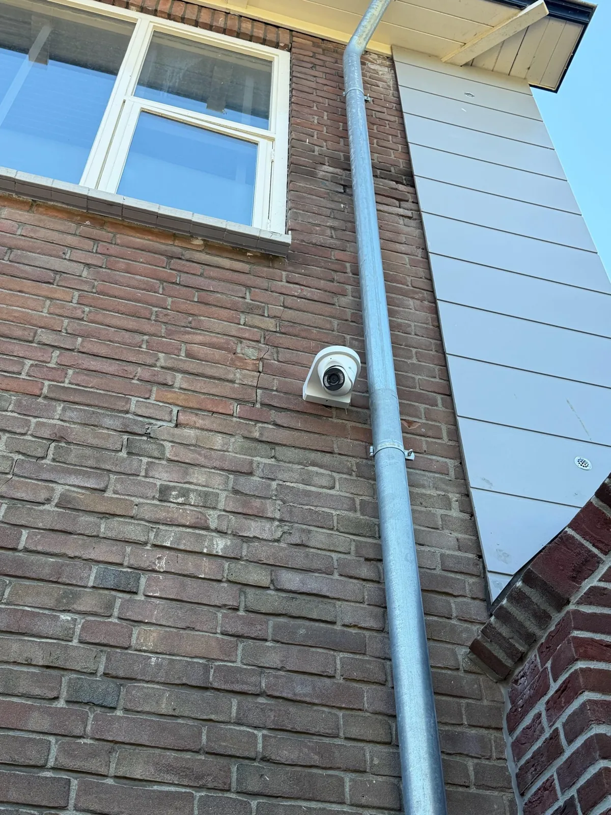 VIGI-turret op baksteen naast de zinken hemelwaterafvoer, onder een raam, in Buren