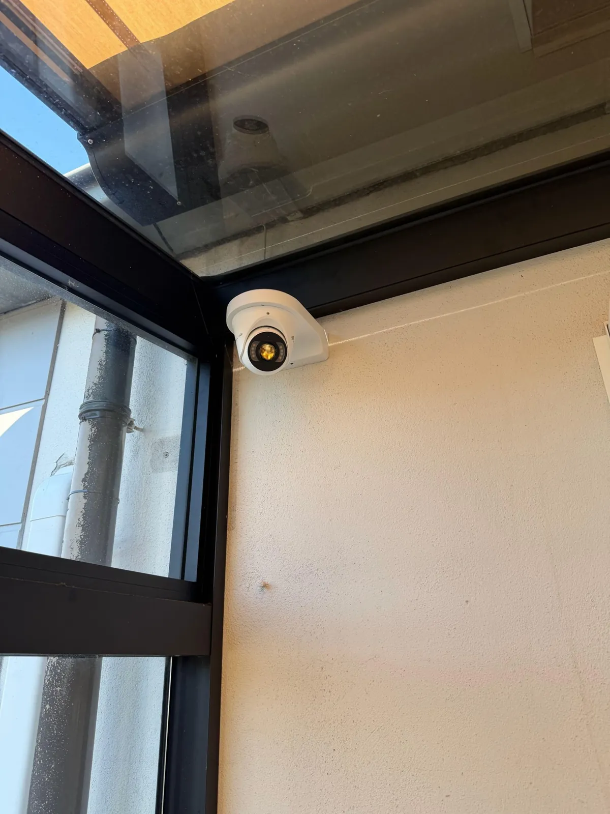 VIGI-turret op een wandbeugel onder de glazen overkapping in Buren, naast een zwart kozijn