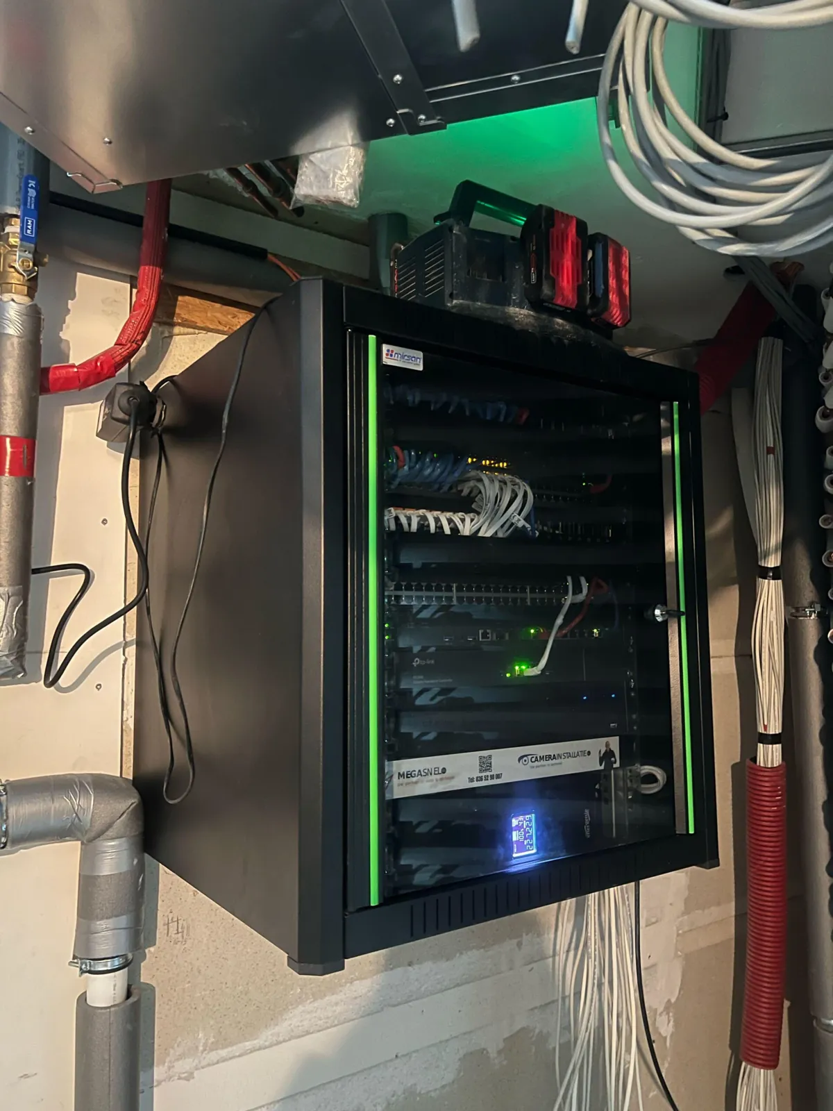 Wandpatchkast met groen licht en patchpanelen in het hotel in Amsterdam, gevoed door dikke kabelbundels