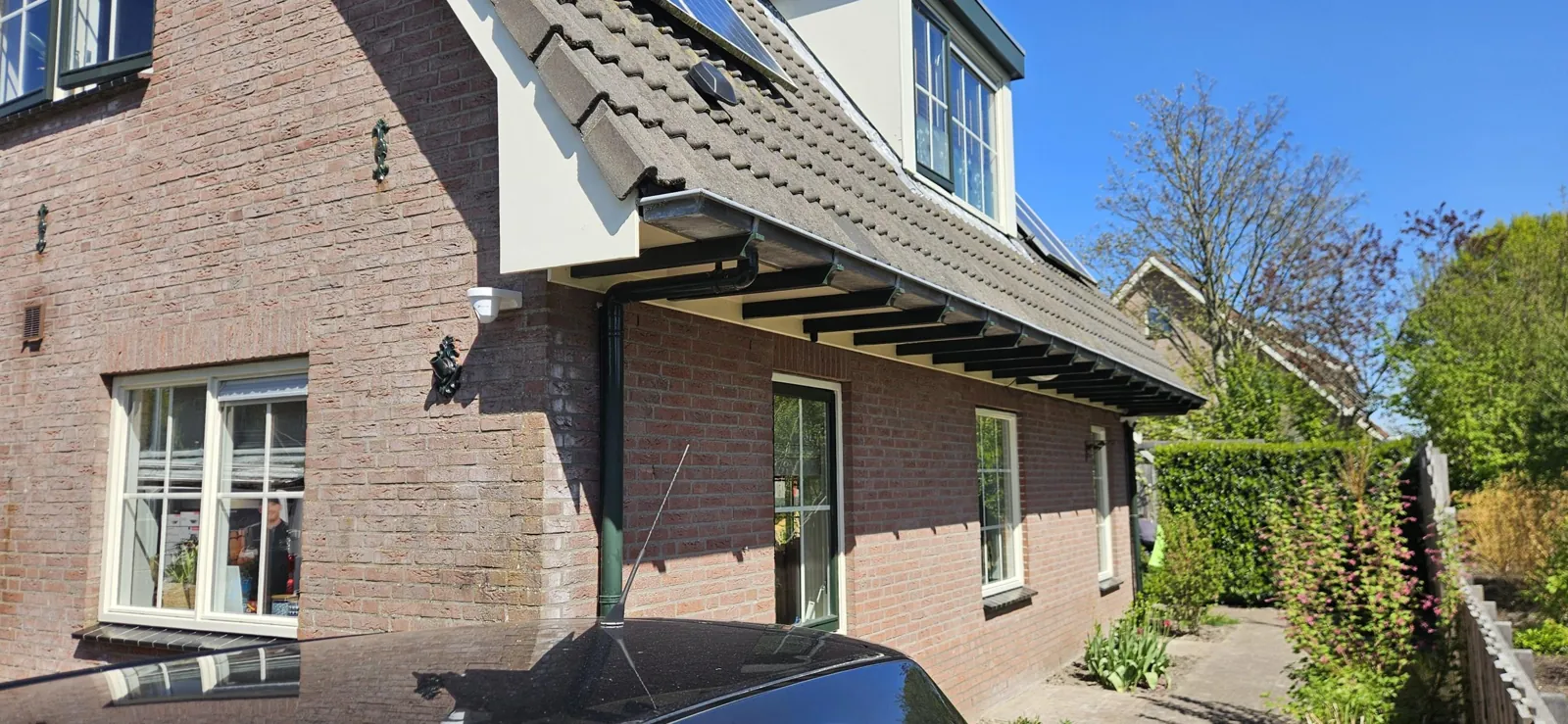 Ruime woning van baksteen, met dakkapel, zonnepanelen en een witte beveiligingscamera
