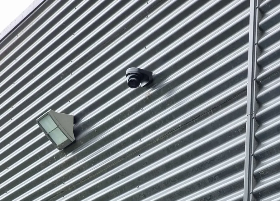 Zwarte dome strak tegen de damwand van het autobedrijf in Almere, naast een buitenlamp