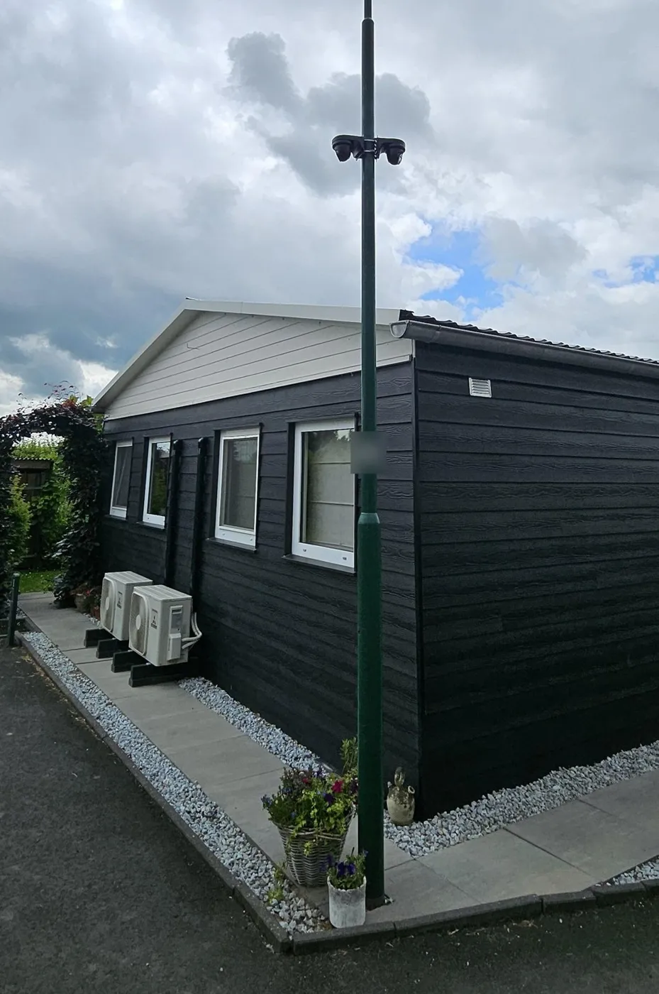 Twee zwarte Dahua-camera's rug aan rug op een groene mast bij de zorgwoning op een erf in Lopikerkapel