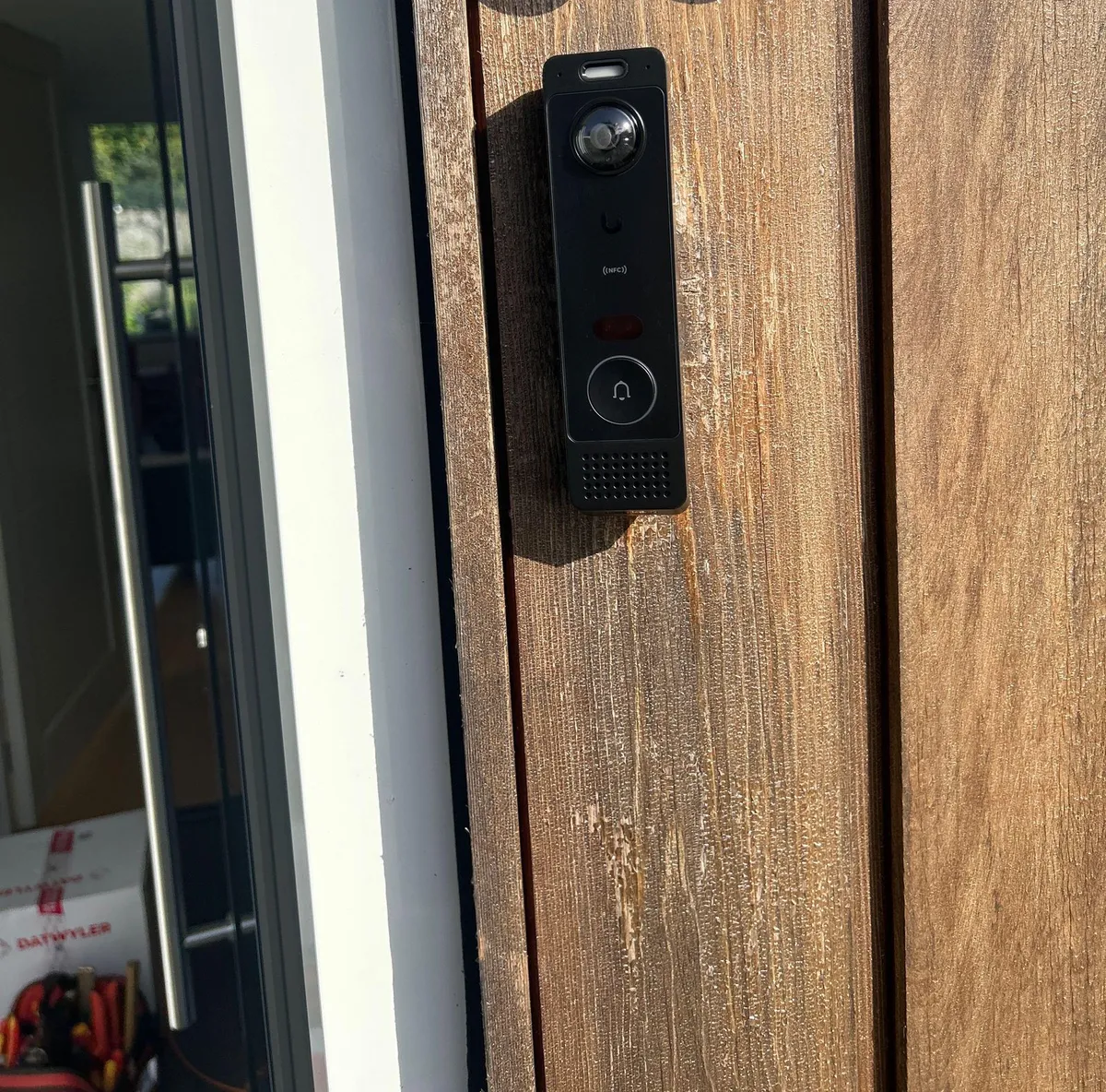 Zwarte UniFi-videodeurbel op een houten gevel naast de voordeur in Bunnik