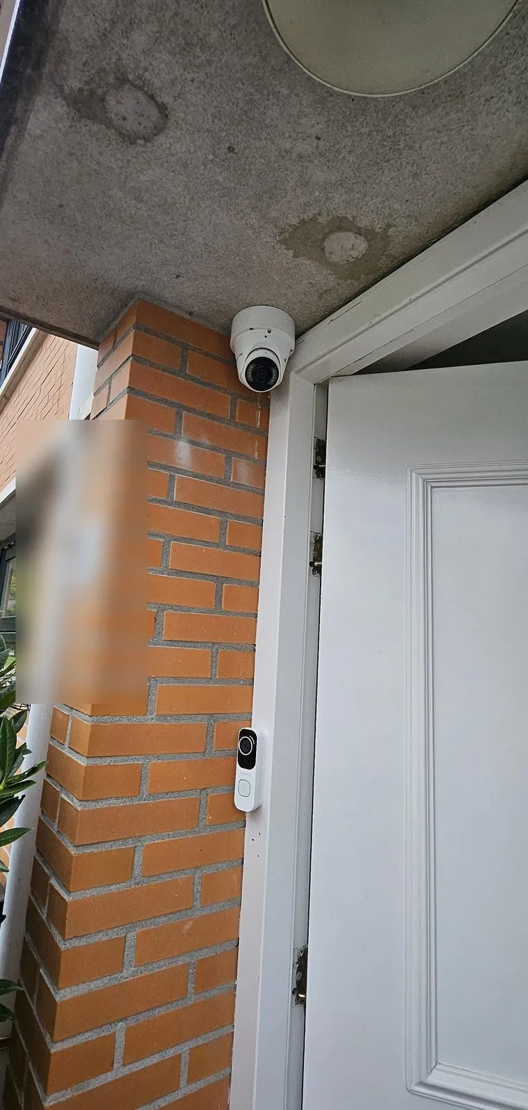Witte VIGI-camera onder de overkapping en een witte videodeurbel naast de voordeur in Maassluis