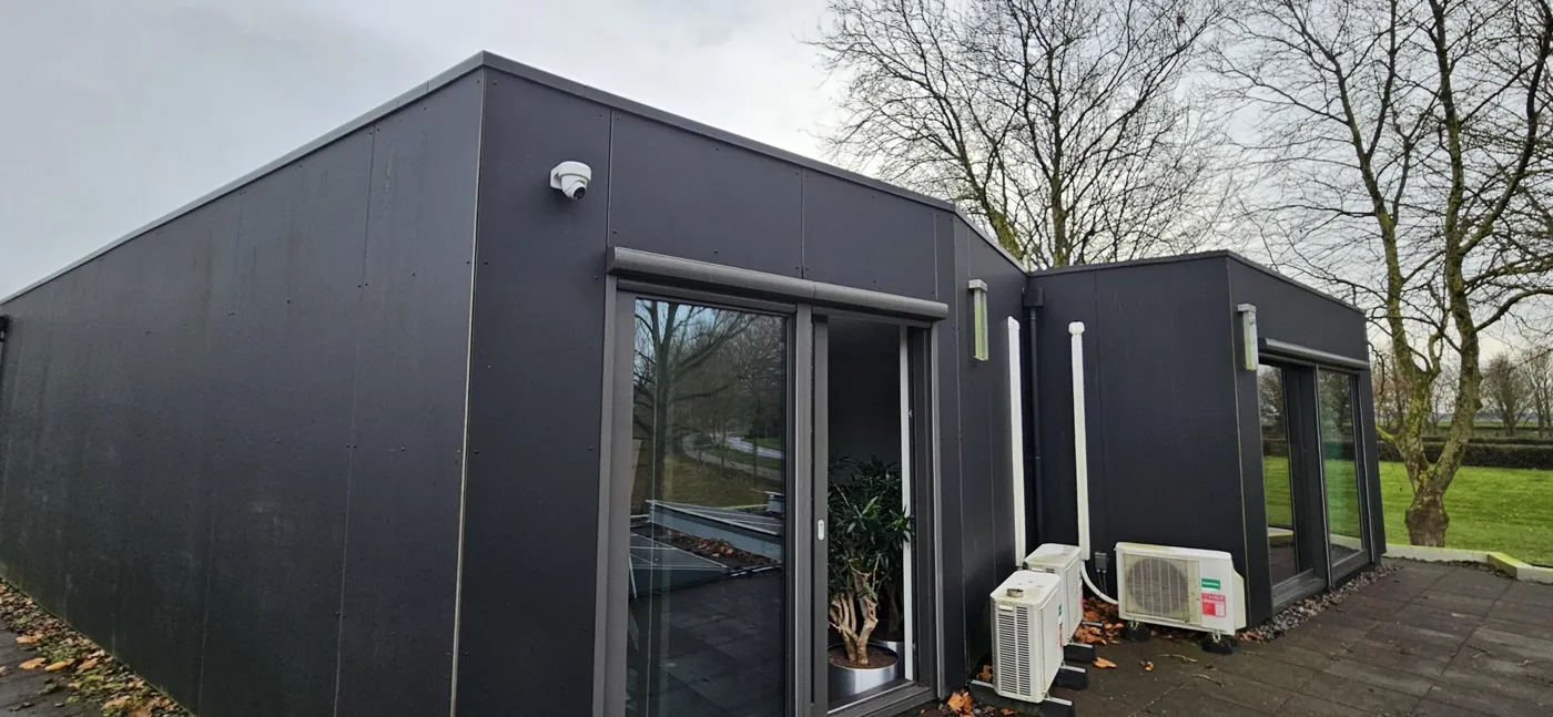 Moderne woning met donkere gevel en camera in Almere